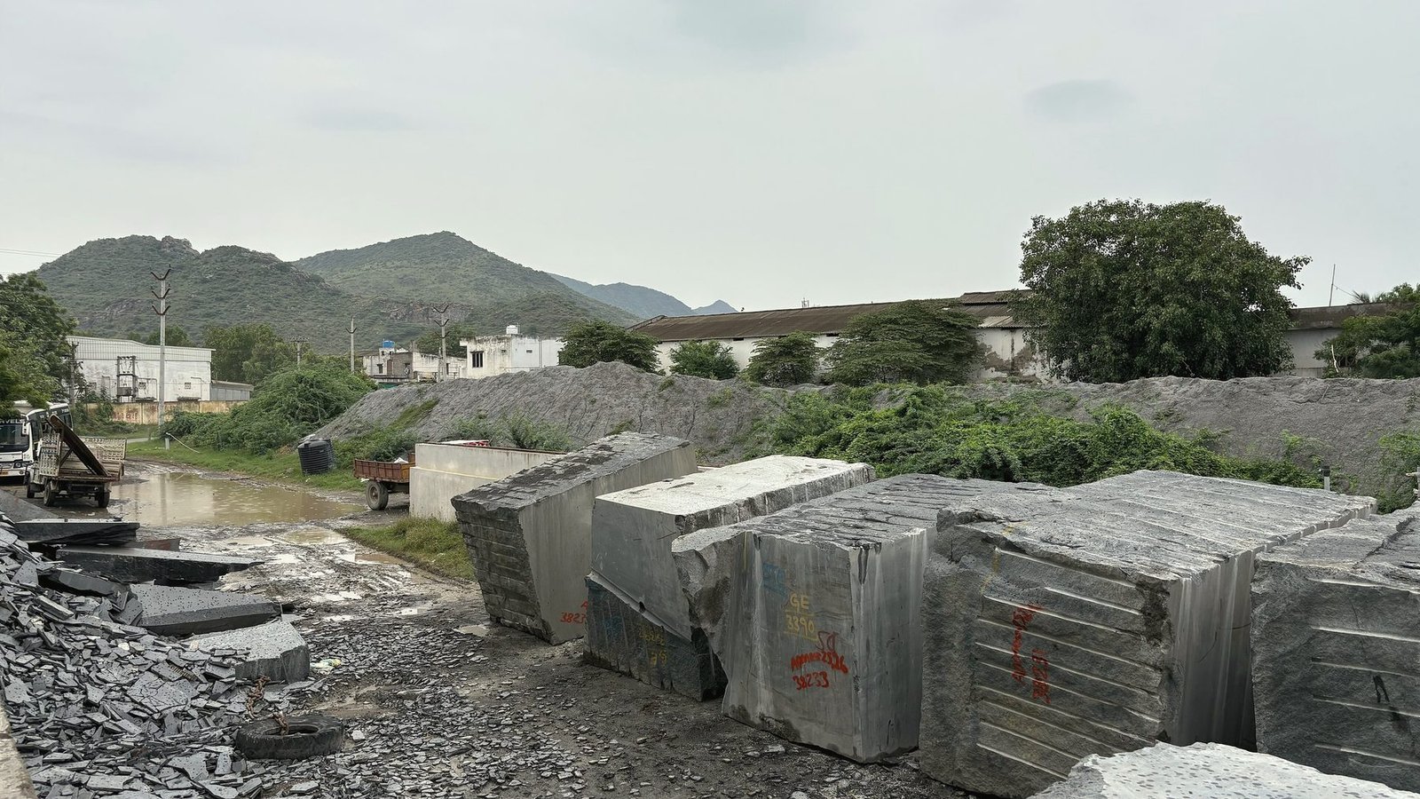 Rough grey granite blocks with painted marks lined up in a stone yard