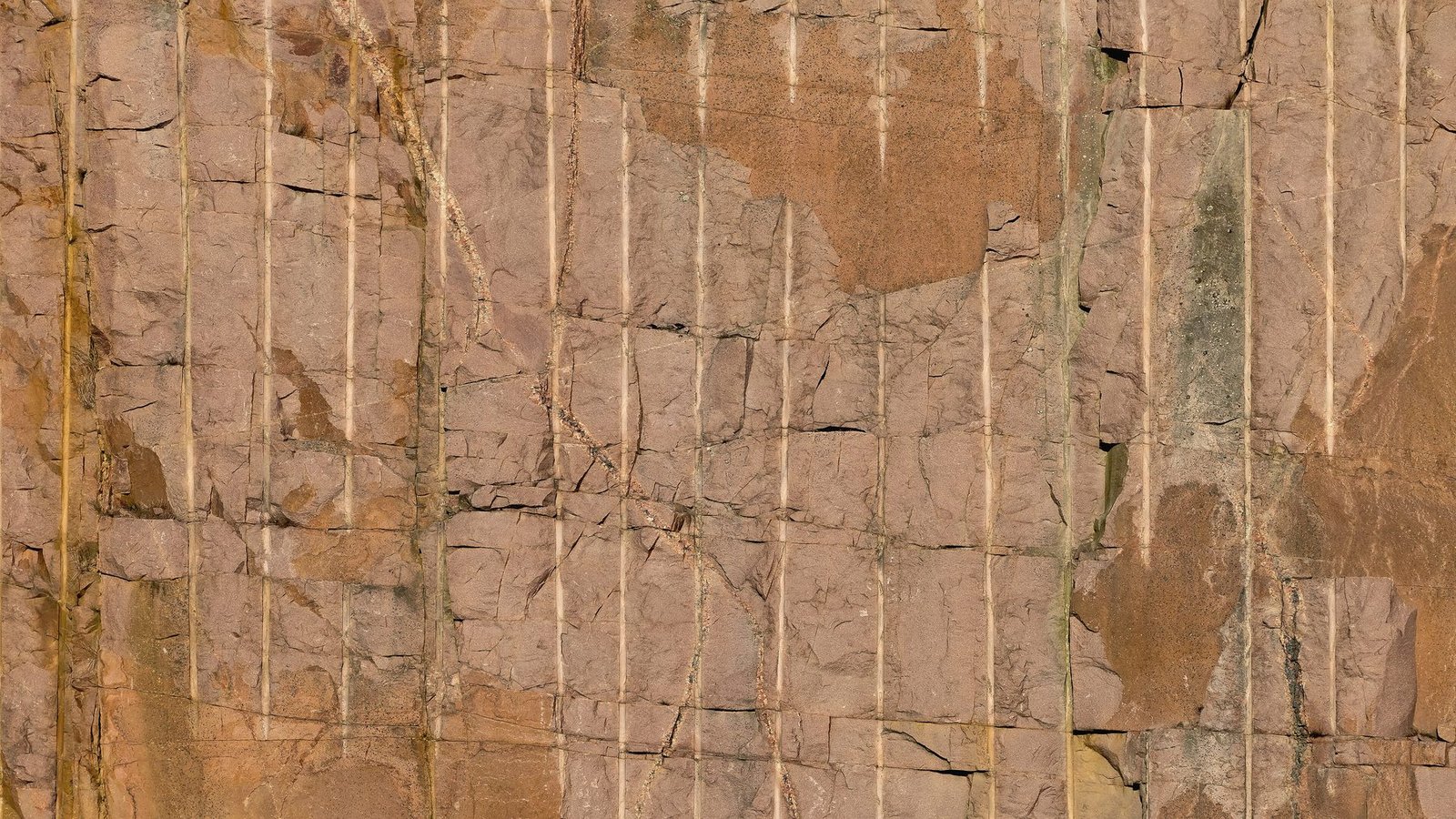 A quarry face scored with evenly spaced vertical drill lines