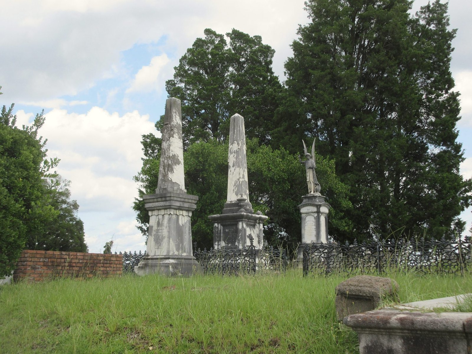 Three obelisks on a raised family plot with trees behind